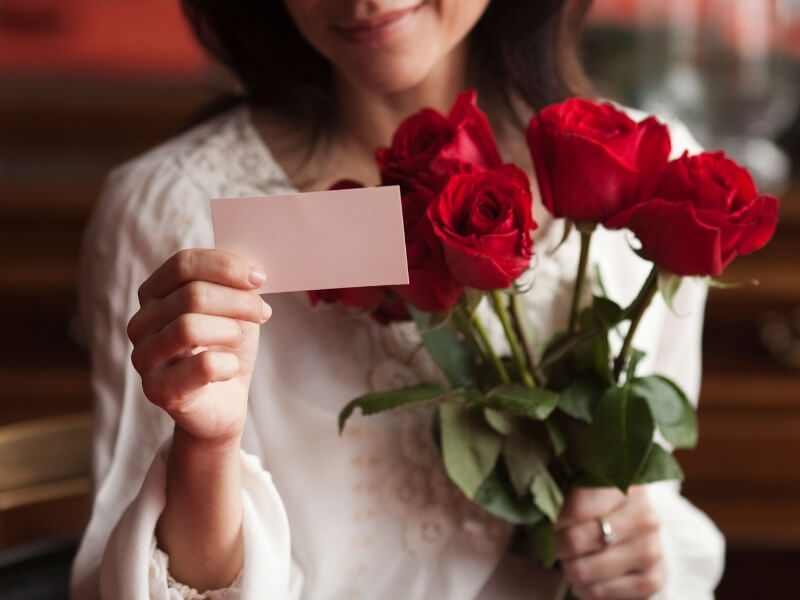 Žena s kyticí růží a pohlednicí na Valentýna.